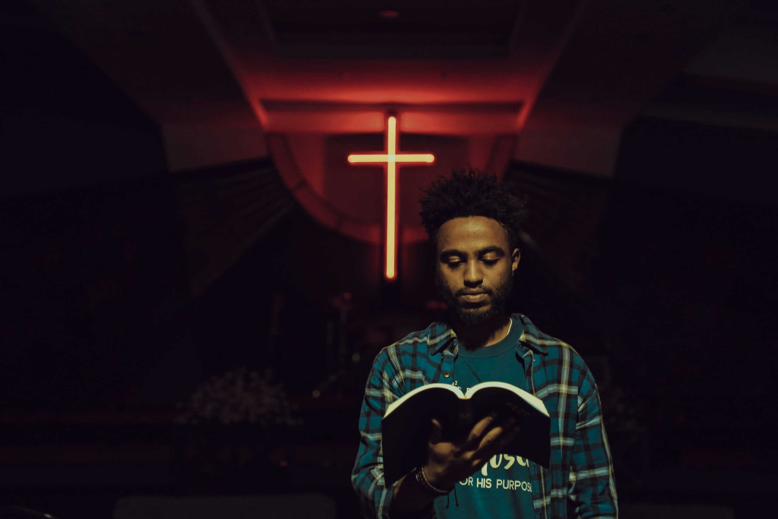 man reading his Bible in front of a cross